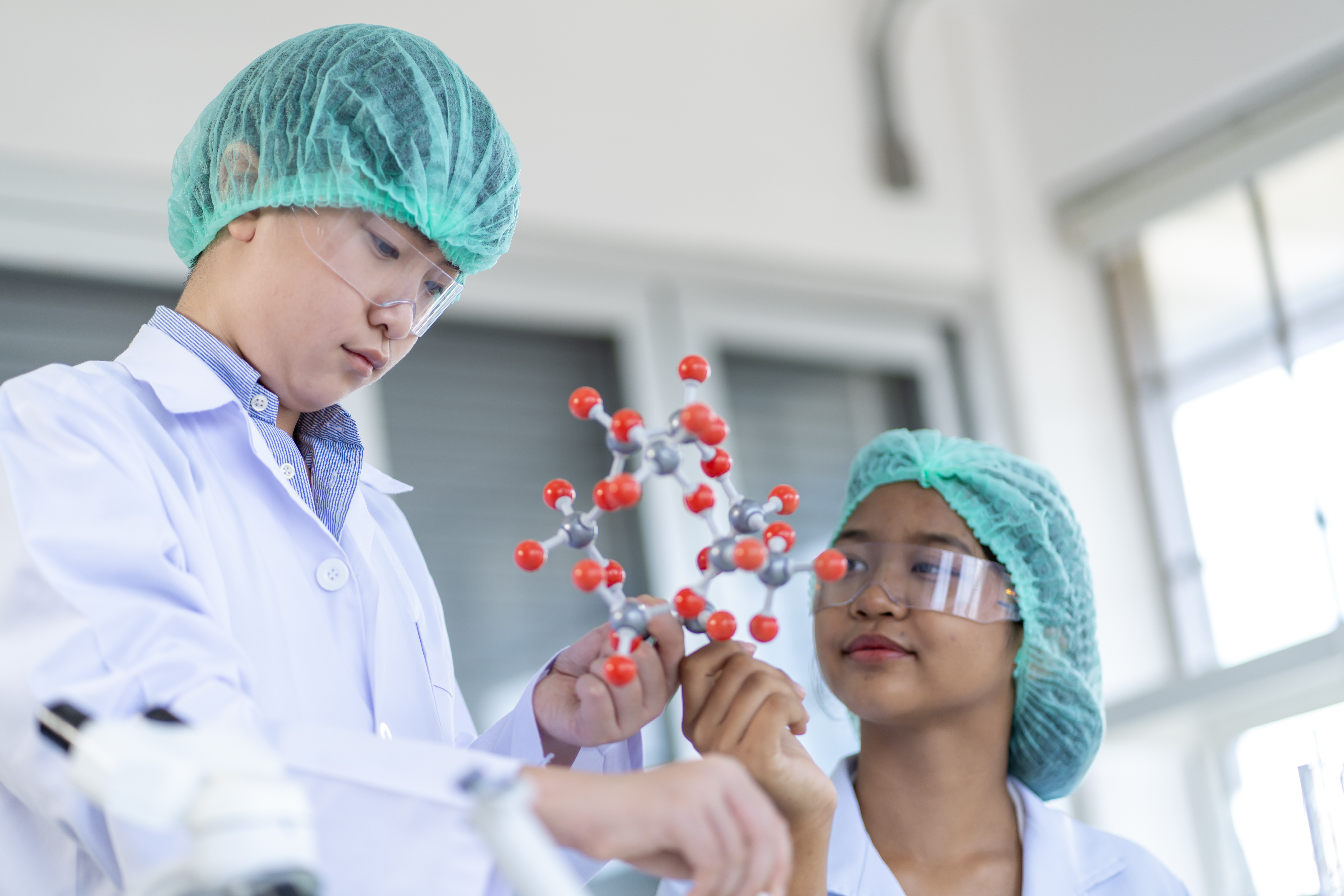 Group of boys and girls who love science Having fun doing experiments in the school lab. It includes a microscope and many test tubes.